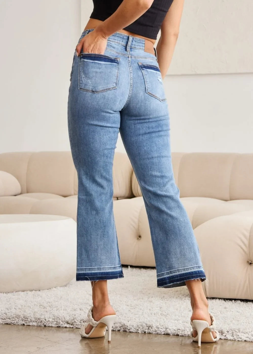 Distressed denim flare jeans with frayed hem detail, shown from the back on a model.