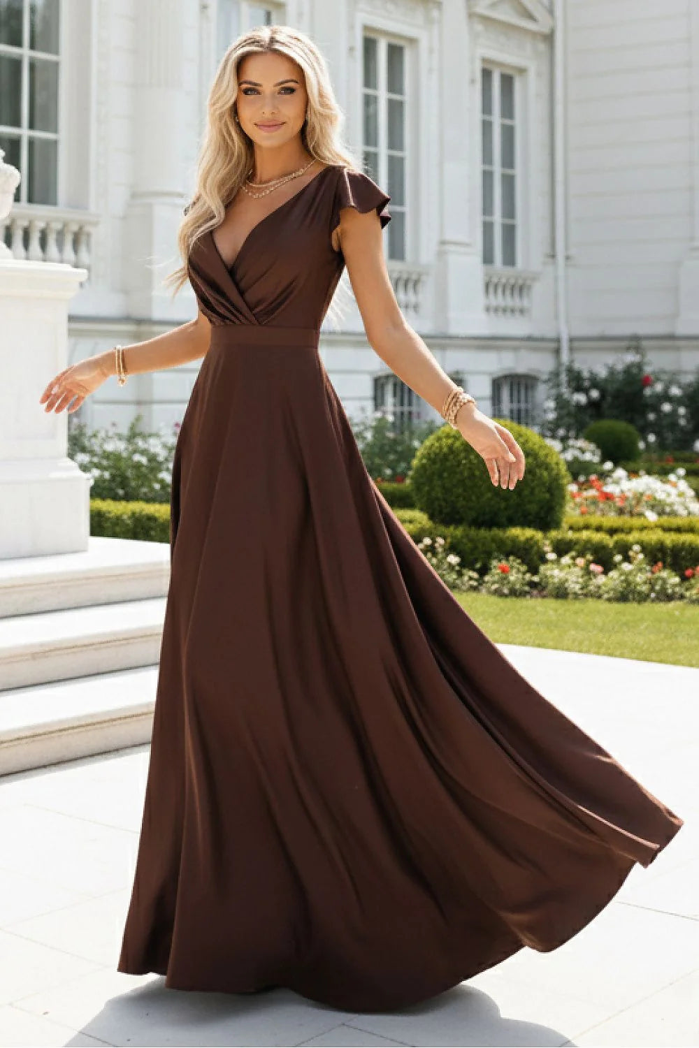 A flowing, dark brown maxi dress with a v-neck and ruffled sleeves, worn by a blonde model outdoors.