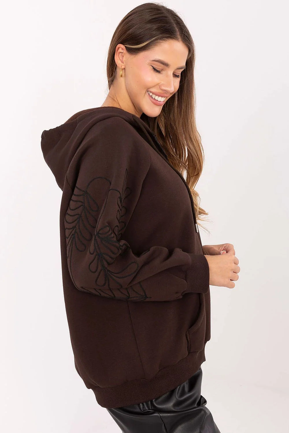 Brown zip-up hoodie with embroidered leaf detail on sleeve, on model.