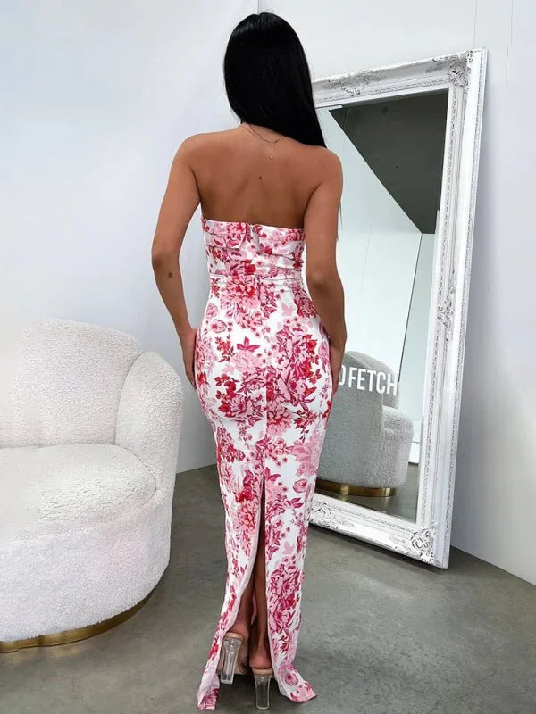 Woman in a strapless pink and white floral maxi dress with a thigh-high slit, seen from the back.