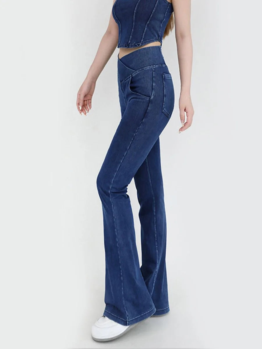 Dark wash denim flare pants with a high waist and a V-shaped waistband, on a model.