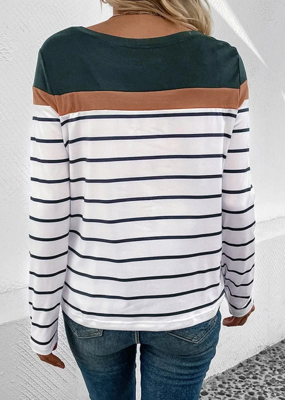 Back view of a woman wearing a long-sleeved shirt with dark green, tan, and navy and white stripes.