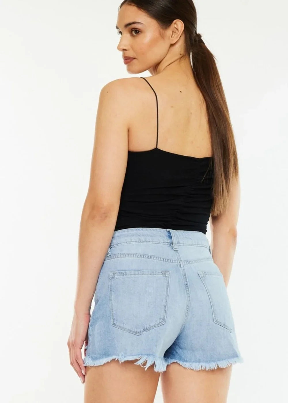 Light wash denim shorts with a frayed hem and distressed details, shown on a model from the back.
