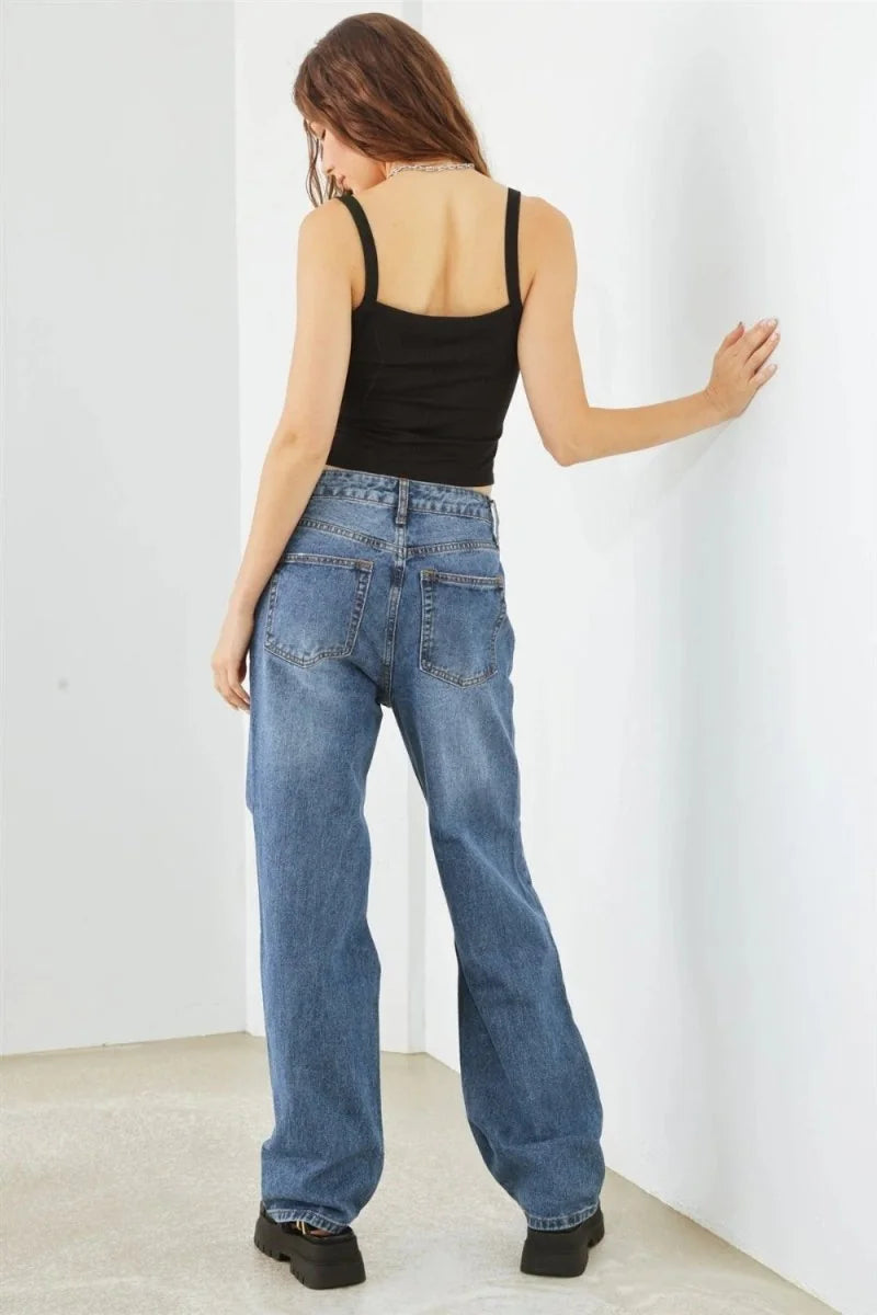Back view of a woman wearing relaxed fit, medium wash denim jeans and a black crop top.