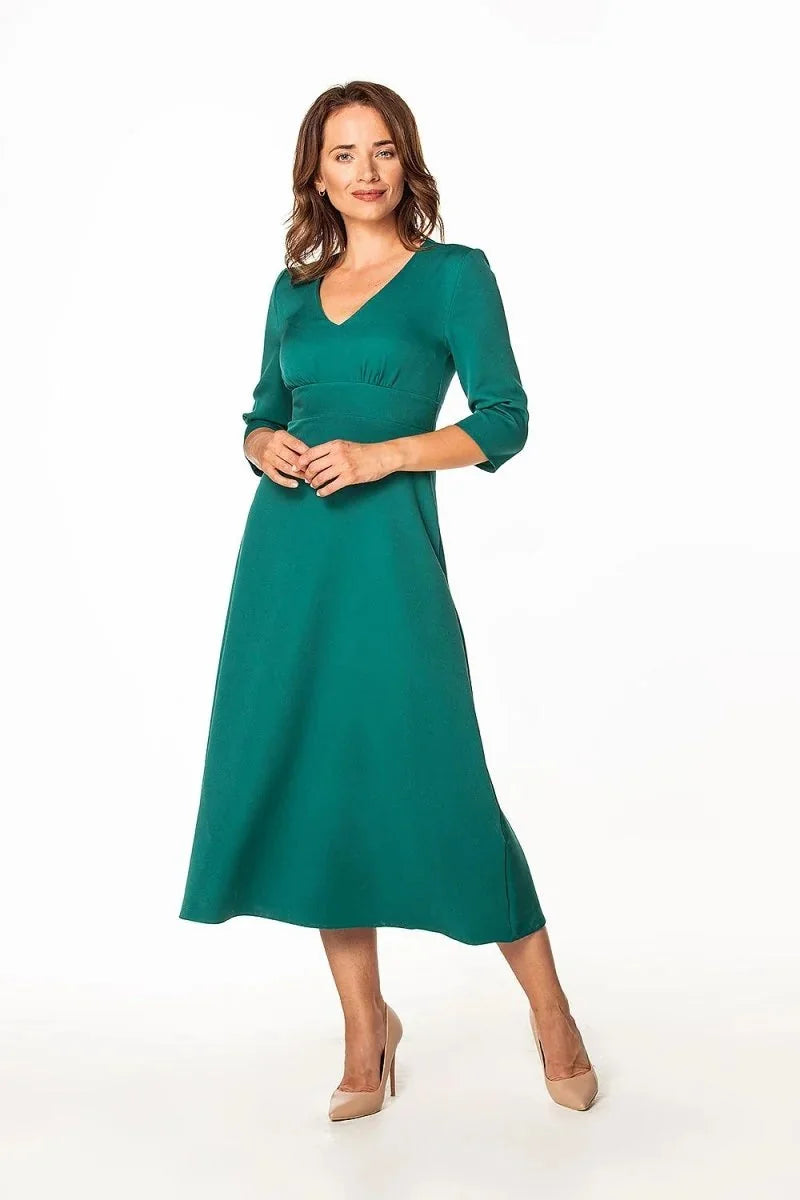 Woman in a teal V-neck midi dress with three-quarter sleeves and nude pumps.
