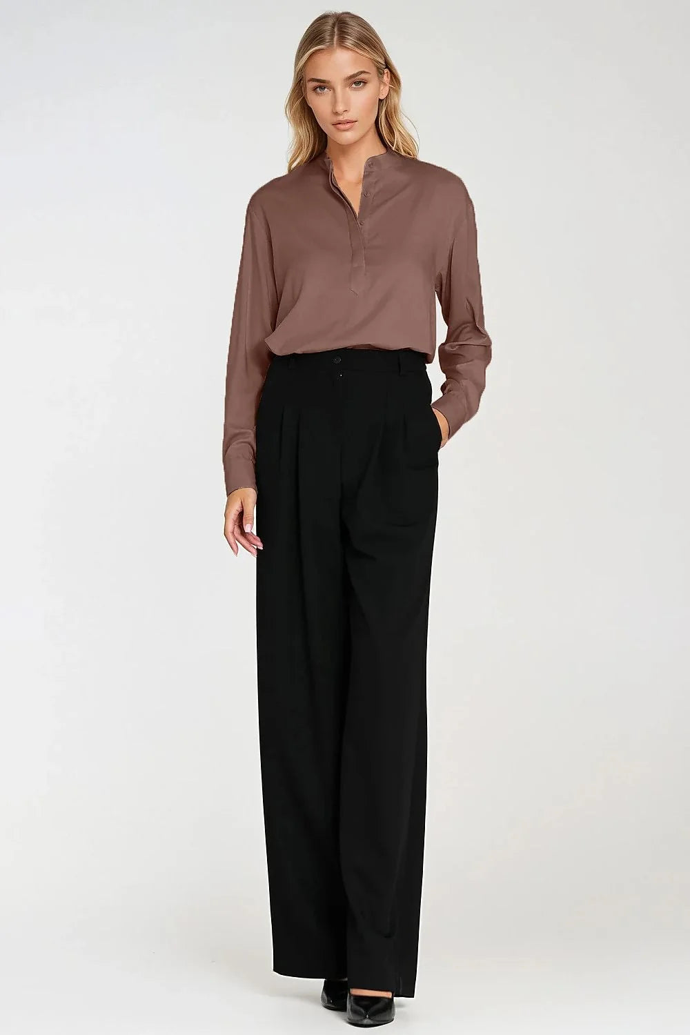 Full-length shot of a woman wearing a brown collared shirt and black wide-leg pants.