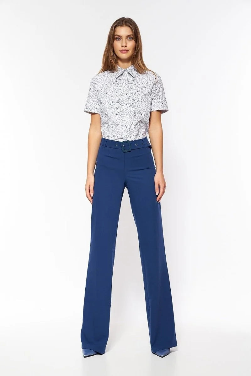 Woman in high-waisted, flared navy blue pants with a matching belt, on a white background.