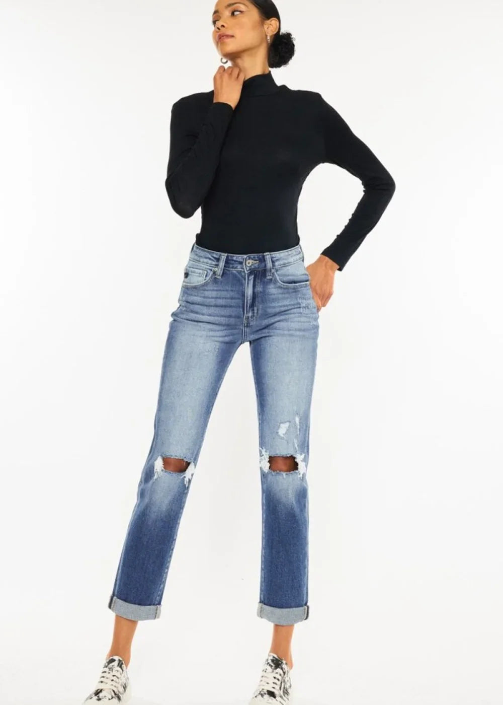 Distressed medium wash denim jeans with ripped knees and cuffed hems, shown on a model.