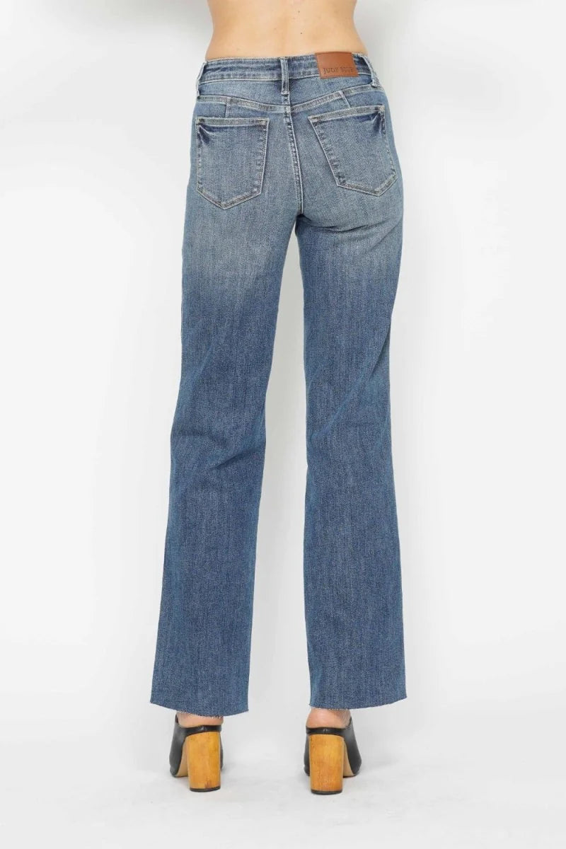 Back view of medium wash, straight-leg jeans with a frayed hem and distressed details.