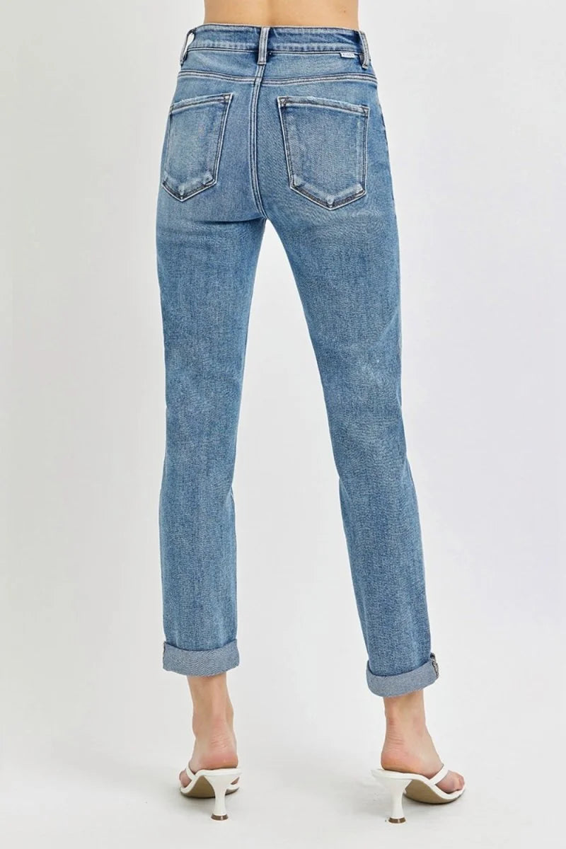 Back view of high-rise, slightly stretchy, light blue denim jeans with rolled cuffs and distressed details.