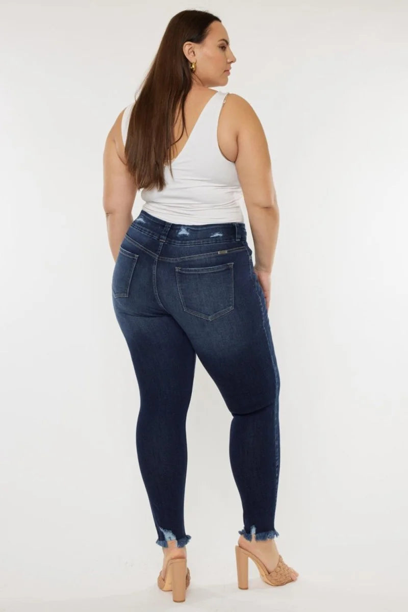 Dark wash, distressed denim jeans with frayed hems, shown from the back on a model.