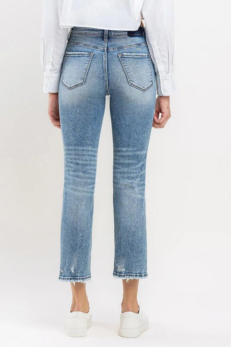 Back view of light wash distressed denim jeans with frayed hem and straight leg fit.