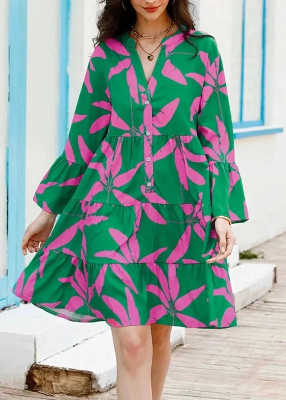 Green tiered mini dress with pink leaf print, V-neck, and bell sleeves.