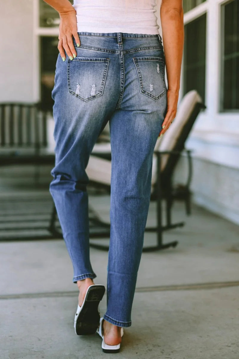 Distressed blue denim jeans with a relaxed fit, showing back pockets and frayed details.