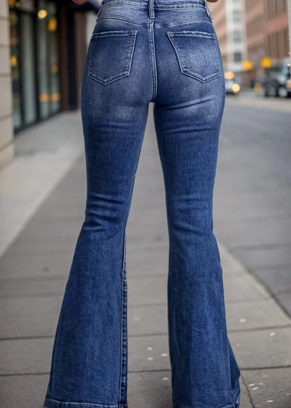 Back view of medium wash distressed denim flare jeans on a model.