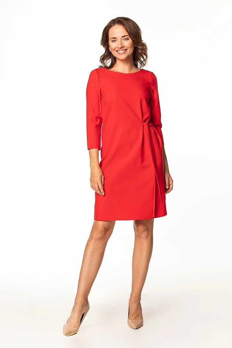 Full-length shot of a woman in a red dress with a cinched waist detail and nude pumps.
