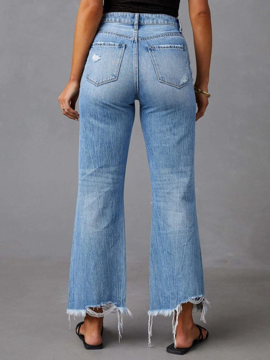 Back view of light wash distressed denim jeans with frayed hem and a regular fit.