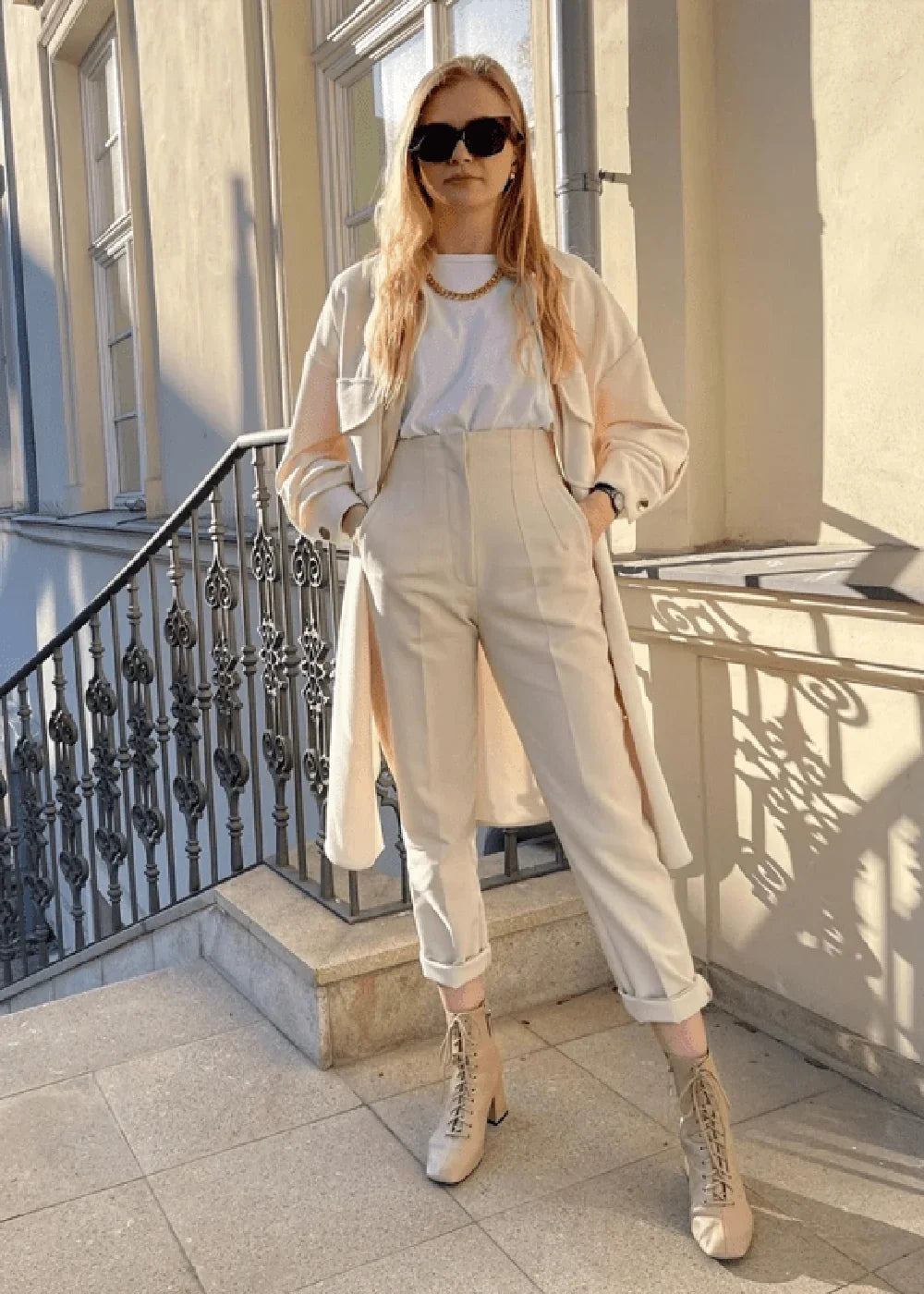 Cream high-waisted trousers with a folded hem, styled on a model.