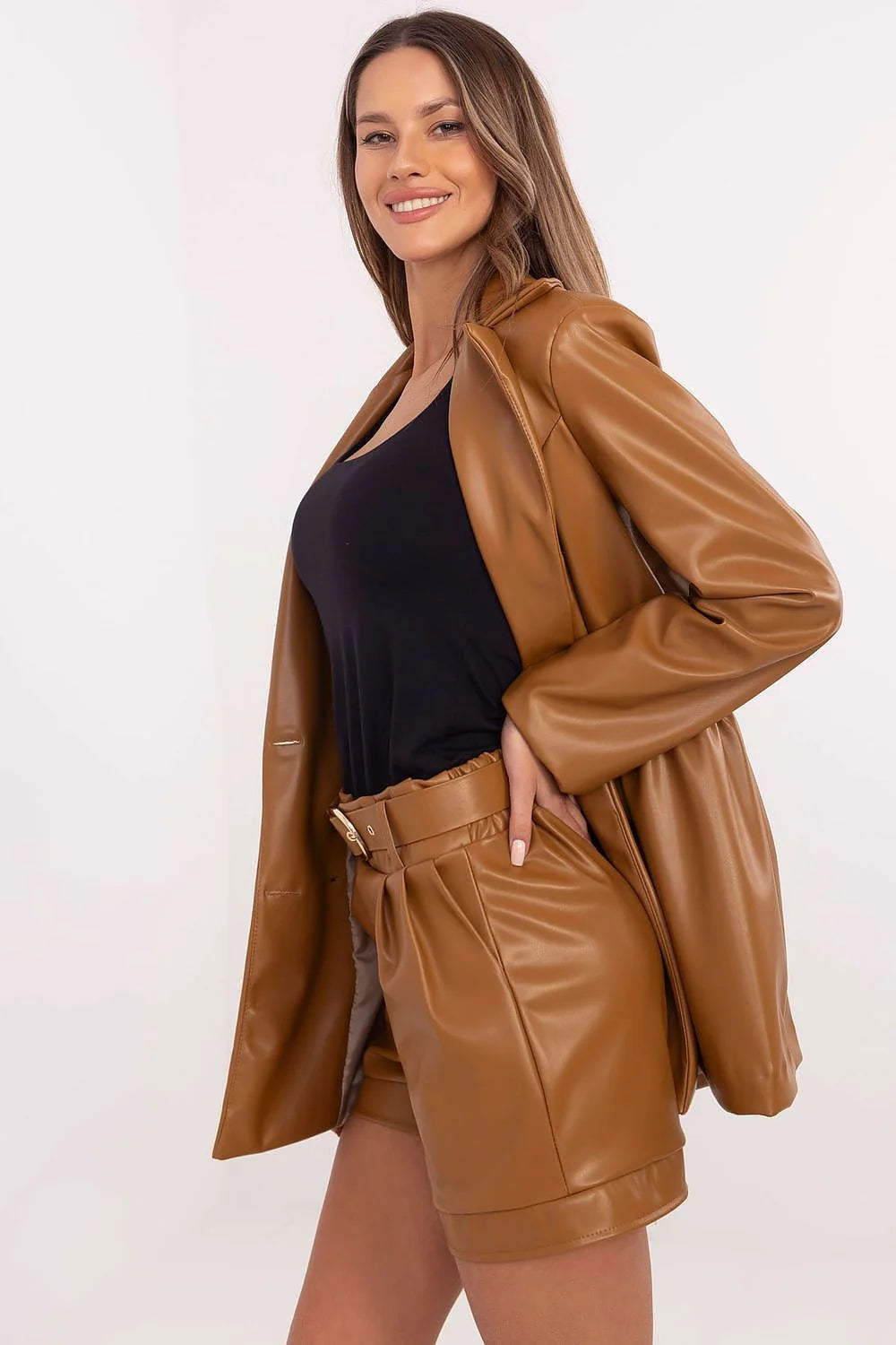 Tan faux leather blazer and high-waisted shorts with belted waist on a smiling model.
