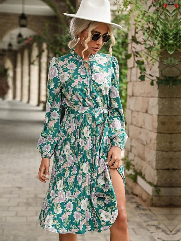Green floral print midi dress with tie neck and pleated skirt, worn by a model outdoors.