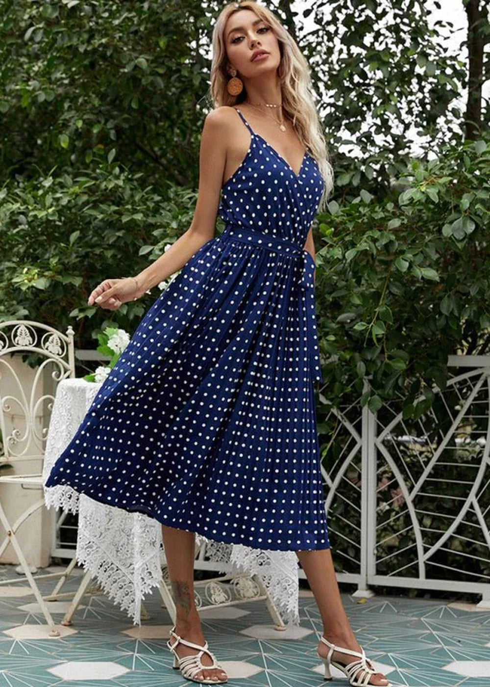 Navy blue polka dot midi dress with pleats and white strappy sandals.