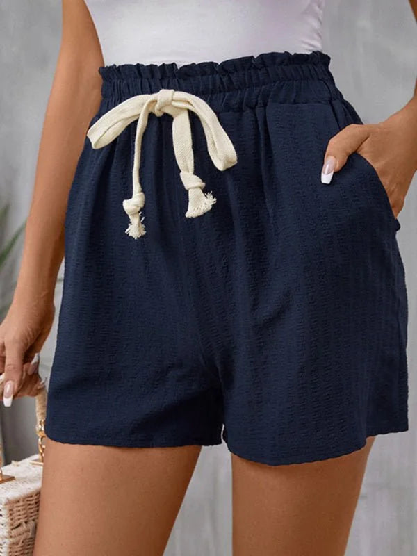 Navy blue textured shorts with a drawstring waist and side pockets, shown on a model.