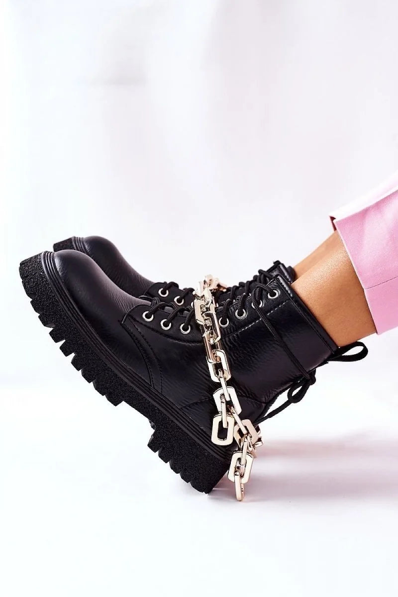 Black faux leather combat boots with silver chain detail, on a white background.