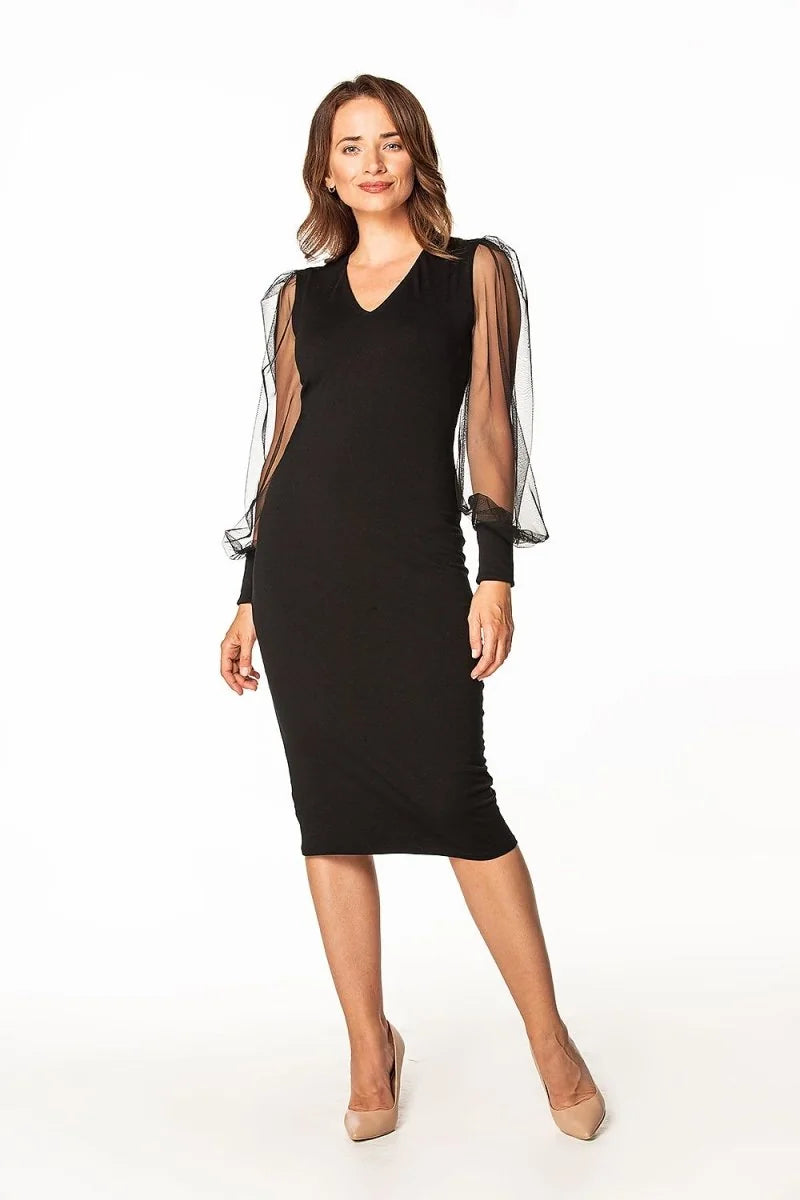 Woman in a black V-neck dress with sheer, voluminous sleeves and nude pumps.
