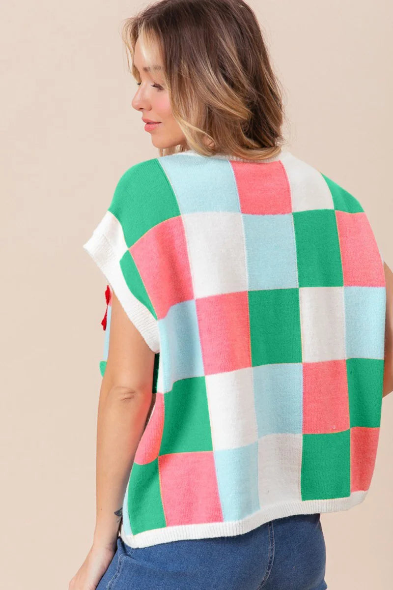 Back view of a sleeveless knit vest with a colorful checkered pattern in green, coral, light blue, and white.