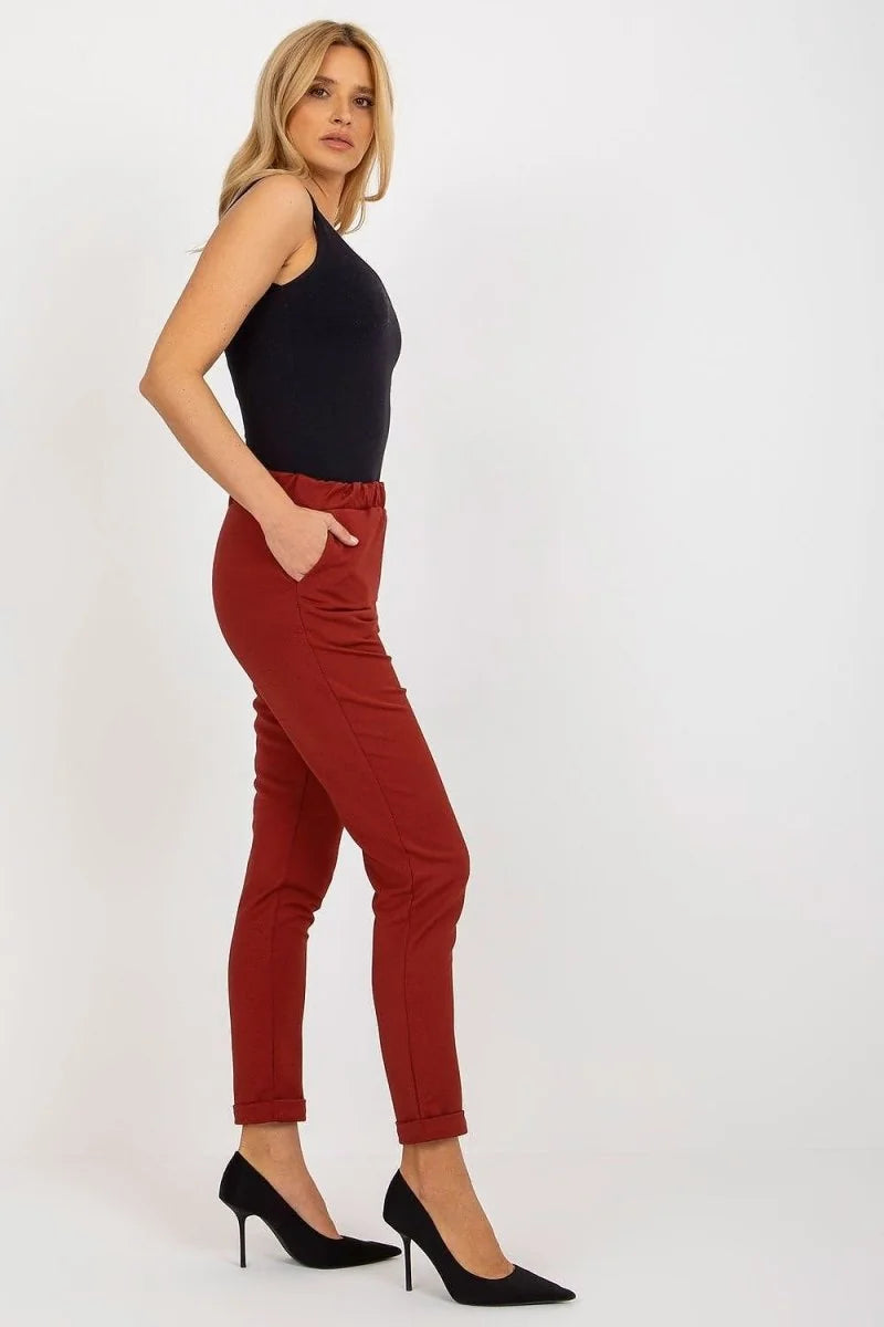 Red high-waisted trousers with a cuffed hem, worn by a model with black heels.