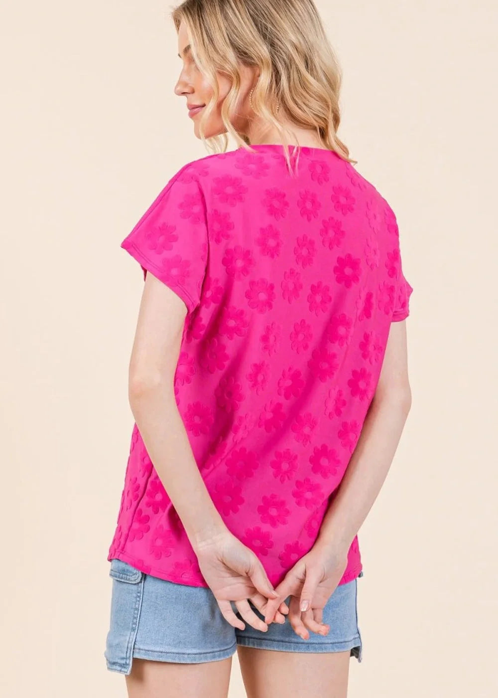 Fuchsia floral textured short-sleeve top on model with denim shorts.