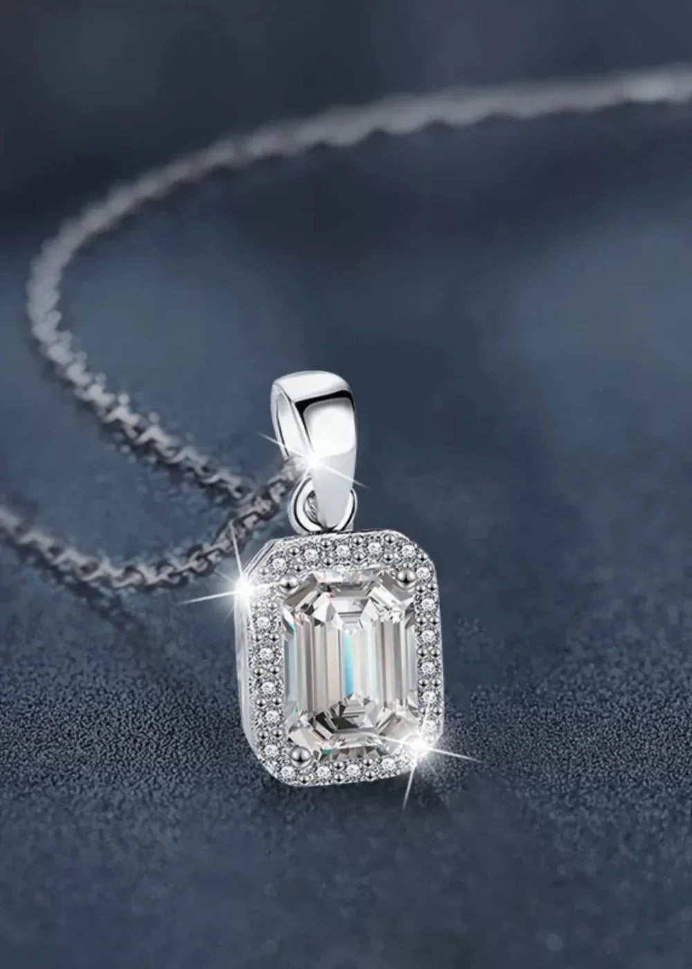 Close-up of a sparkling rectangular moissanite pendant on a silver chain, surrounded by smaller diamonds.