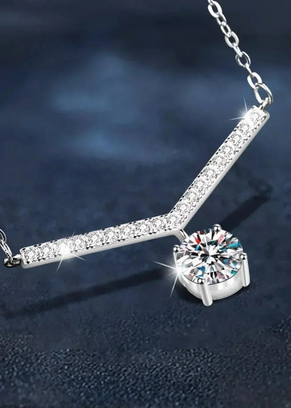 A platinum-plated sterling silver necklace with a V-shaped bar adorned with small, sparkling moissanite stones, and a sing...