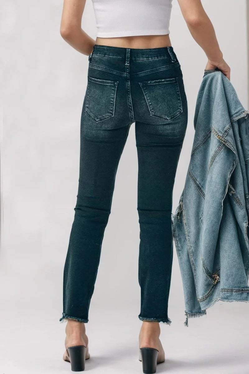 Dark wash skinny jeans with a frayed hem and distressed details, shown from the back on a model.