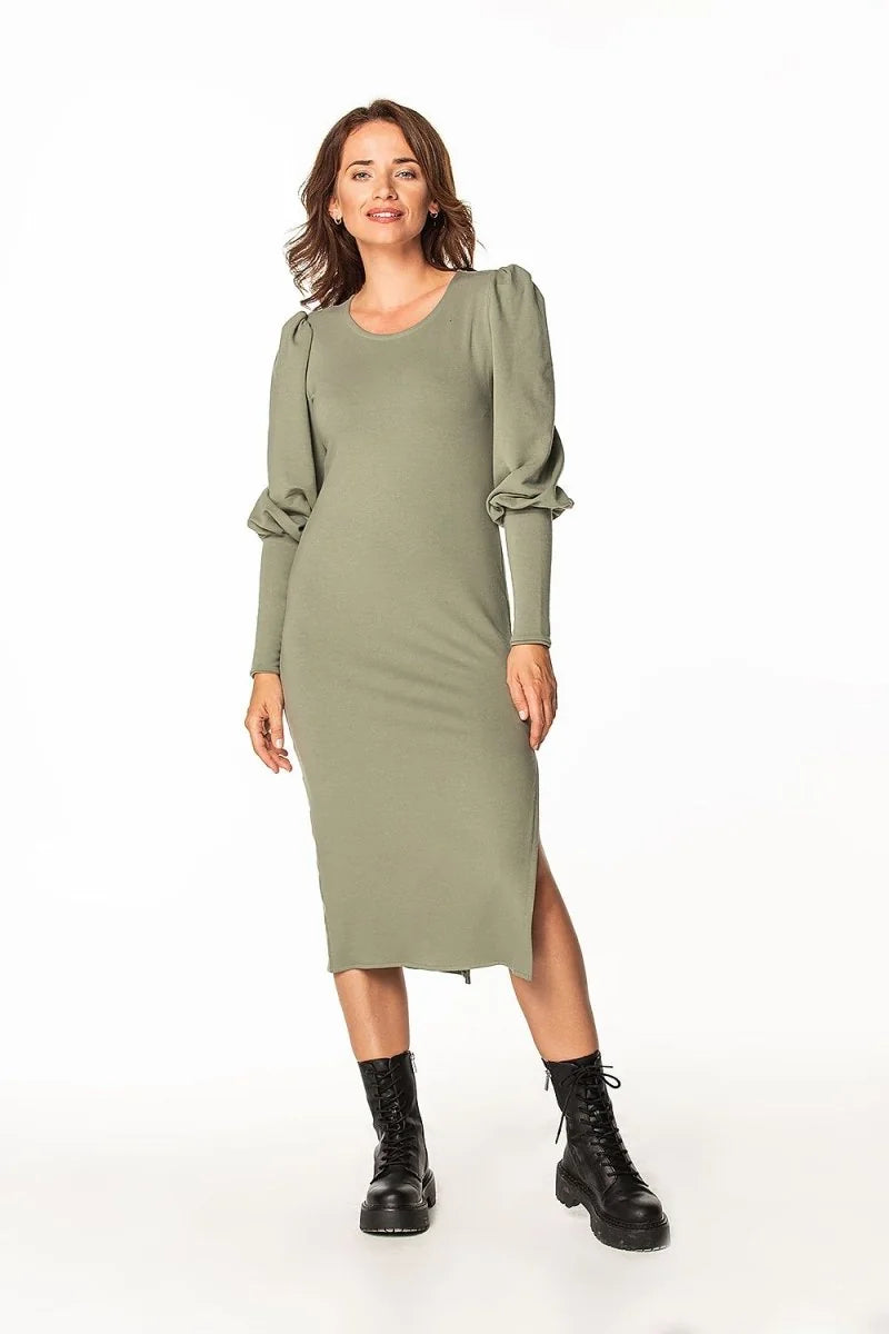 Full-length image of a woman wearing a sage green, long-sleeved midi dress with puffed sleeves and a side slit, paired wit...