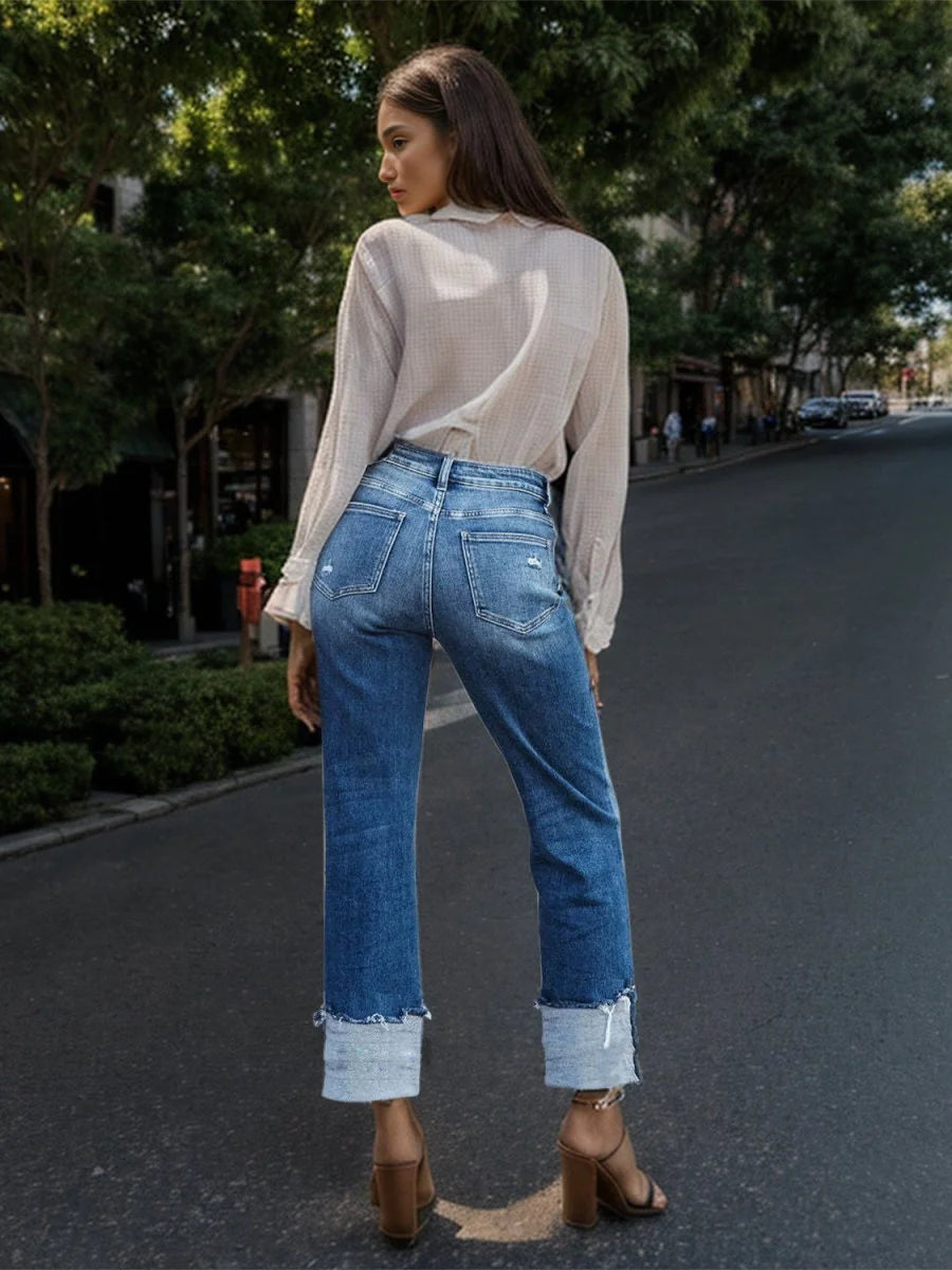 Medium wash denim jeans with frayed cuffs and distressed details.