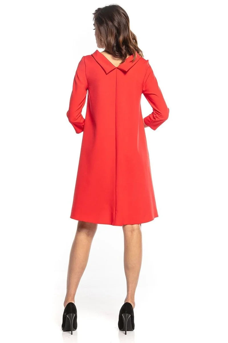 Red trapeze dress with wide collar, long sleeves, and black high heels.