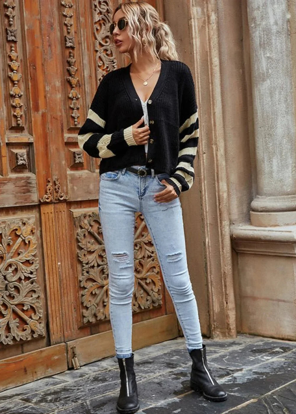 Black and tan striped cardigan with distressed light wash denim jeans, worn by a model.