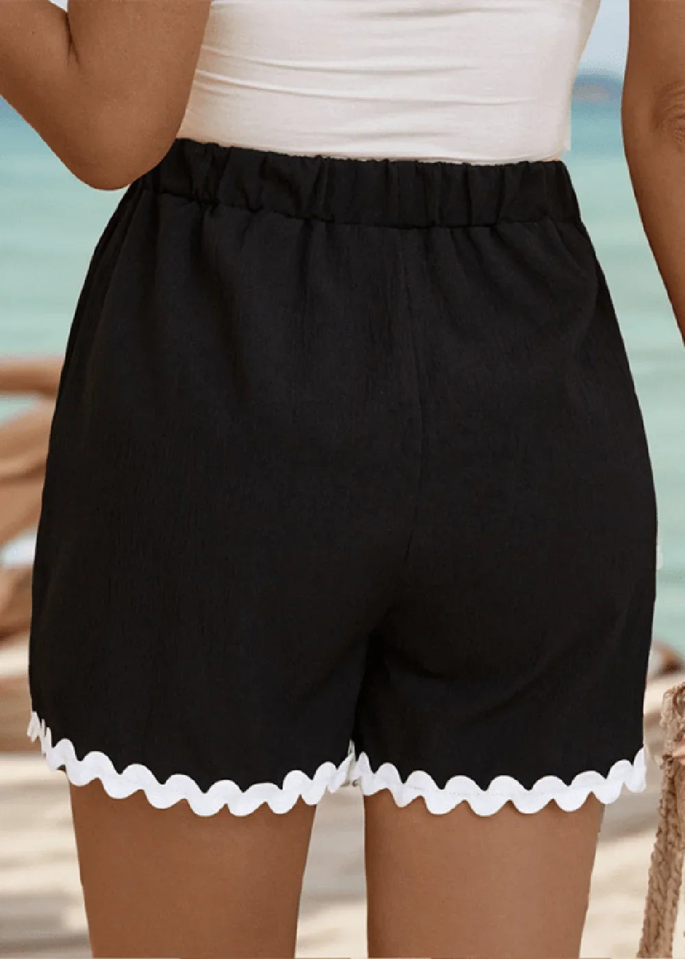 Black shorts with ruffled white trim and elastic waistband, shown from the back.