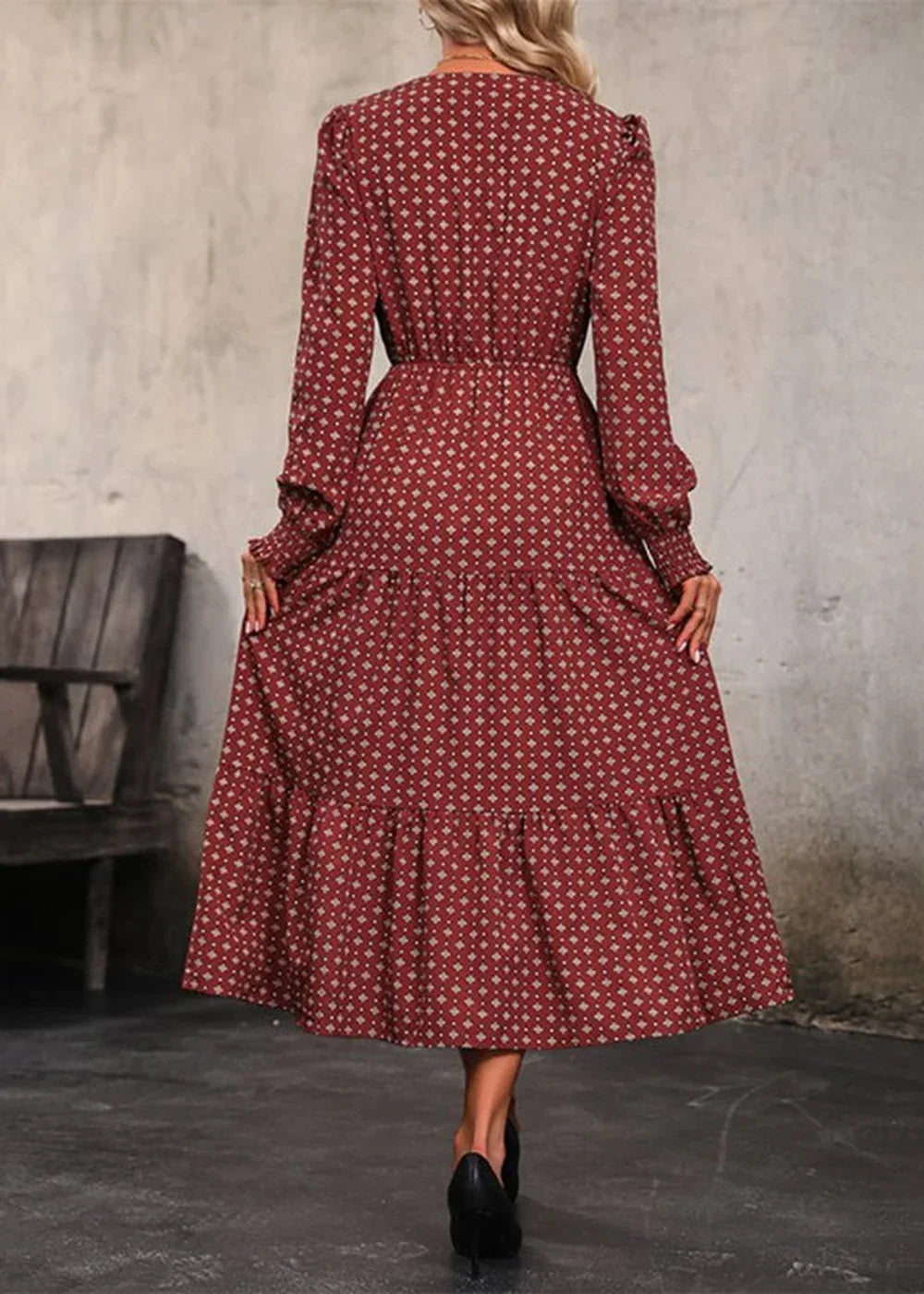 Back view of a red dress with a diamond print, tiered skirt, and long sleeves.