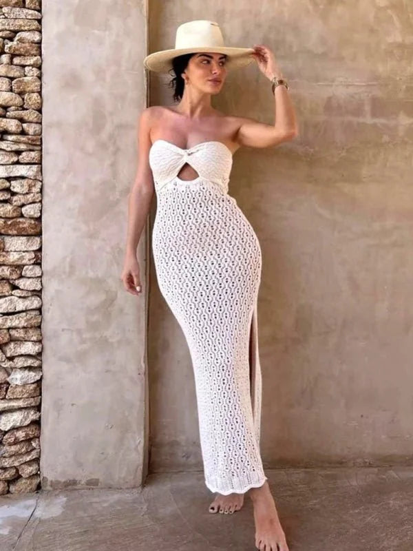 White crochet maxi dress with a cutout bust and a thigh-high slit, worn by a model with a wide-brim hat.