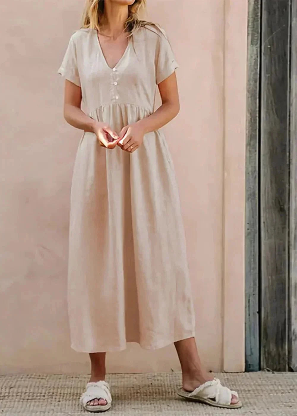 Beige cotton midi dress with V-neck and button detail, on model.