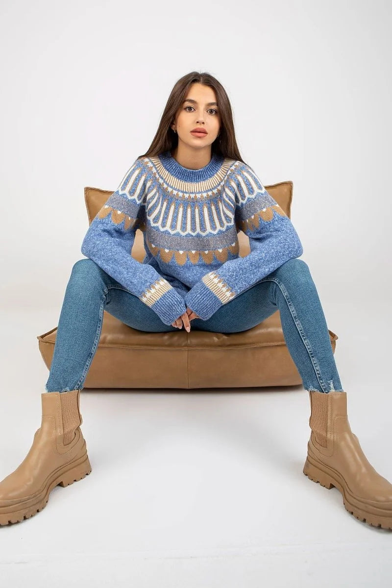 Blue knit sweater with geometric pattern, worn by a model with jeans and tan boots.