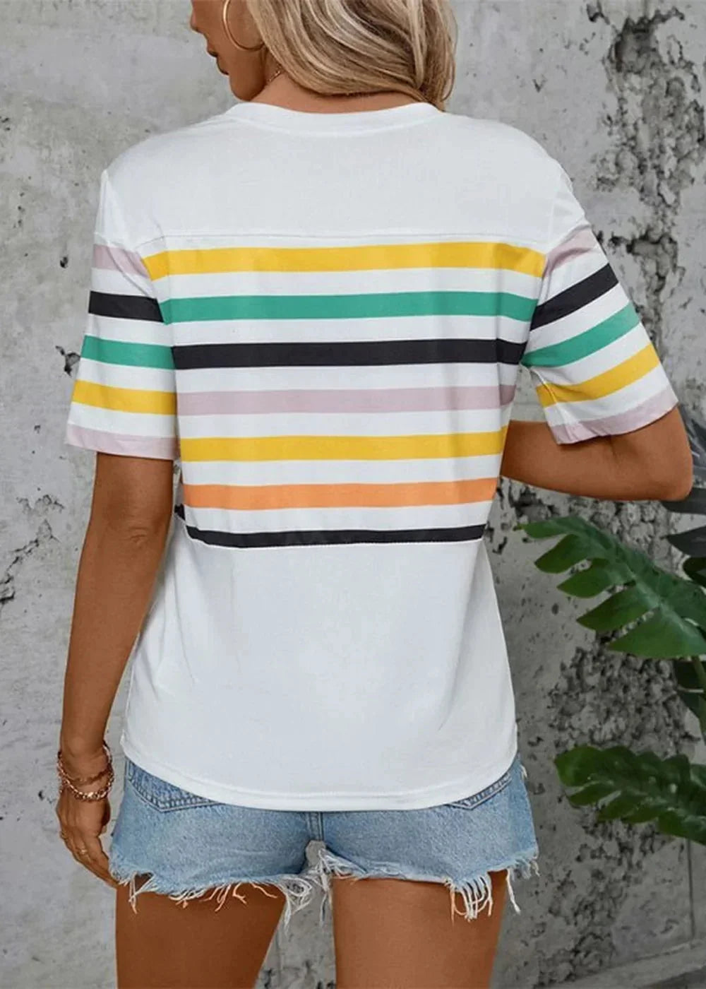 Back view of white t-shirt with horizontal stripes in yellow, green, black, pink, and orange.