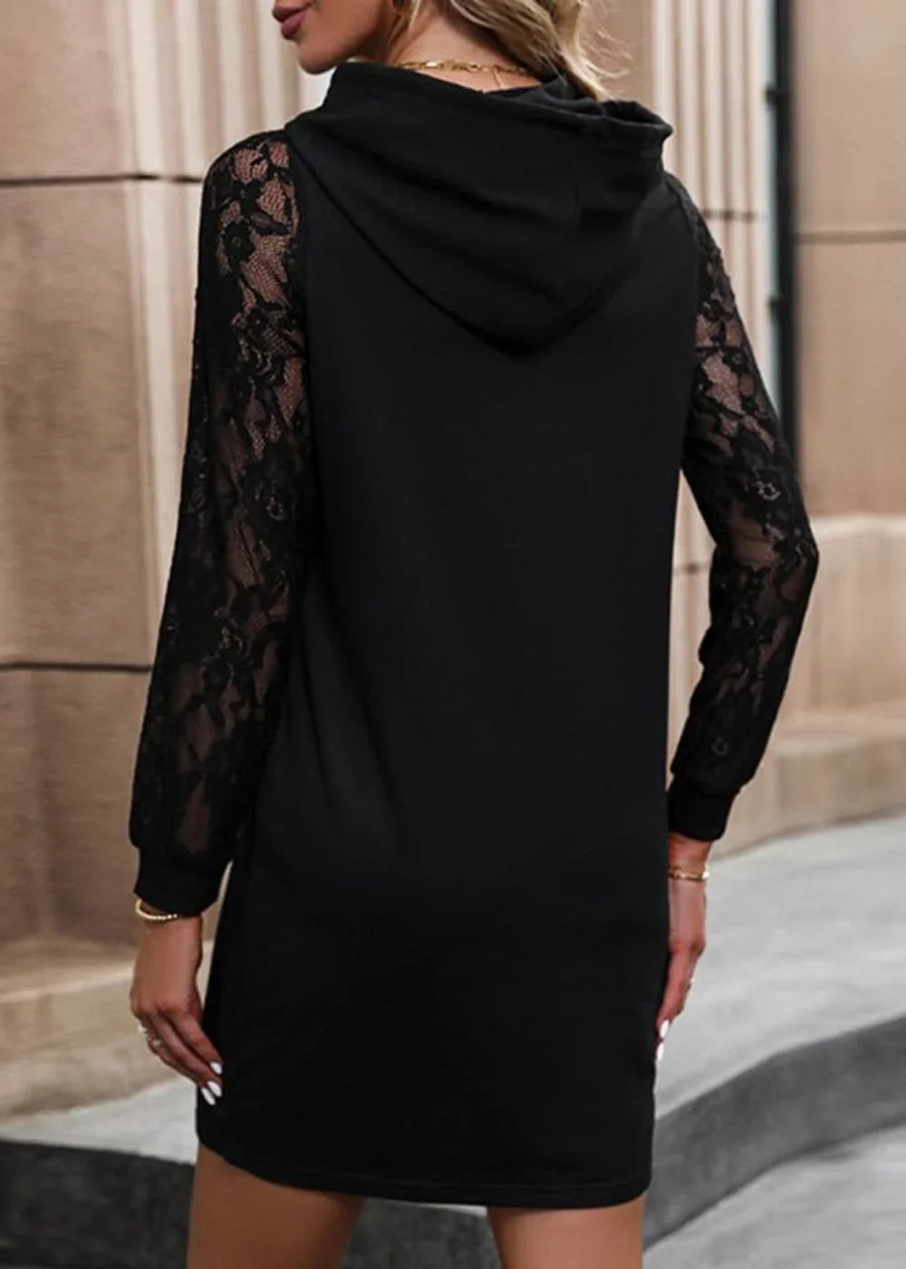 Black hooded sweater dress with sheer lace sleeves, showing the back on a model.