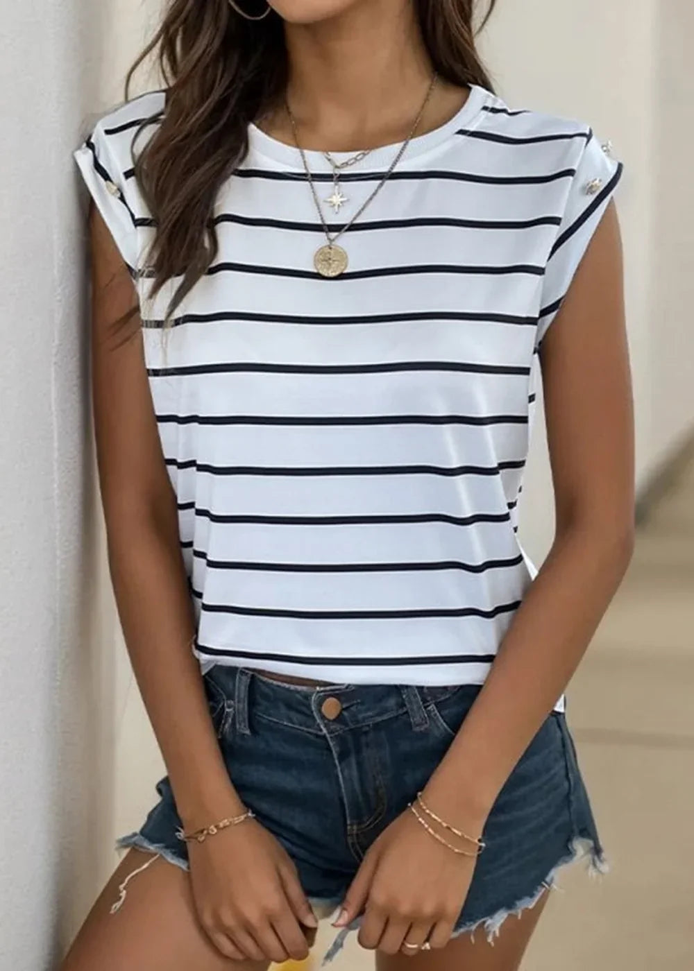 White and black striped t-shirt with rolled sleeves and gold button detail, worn with denim shorts.