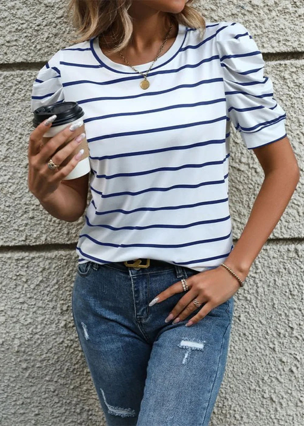 White and navy striped puff-sleeve top with gold-tone belt and distressed denim jeans.