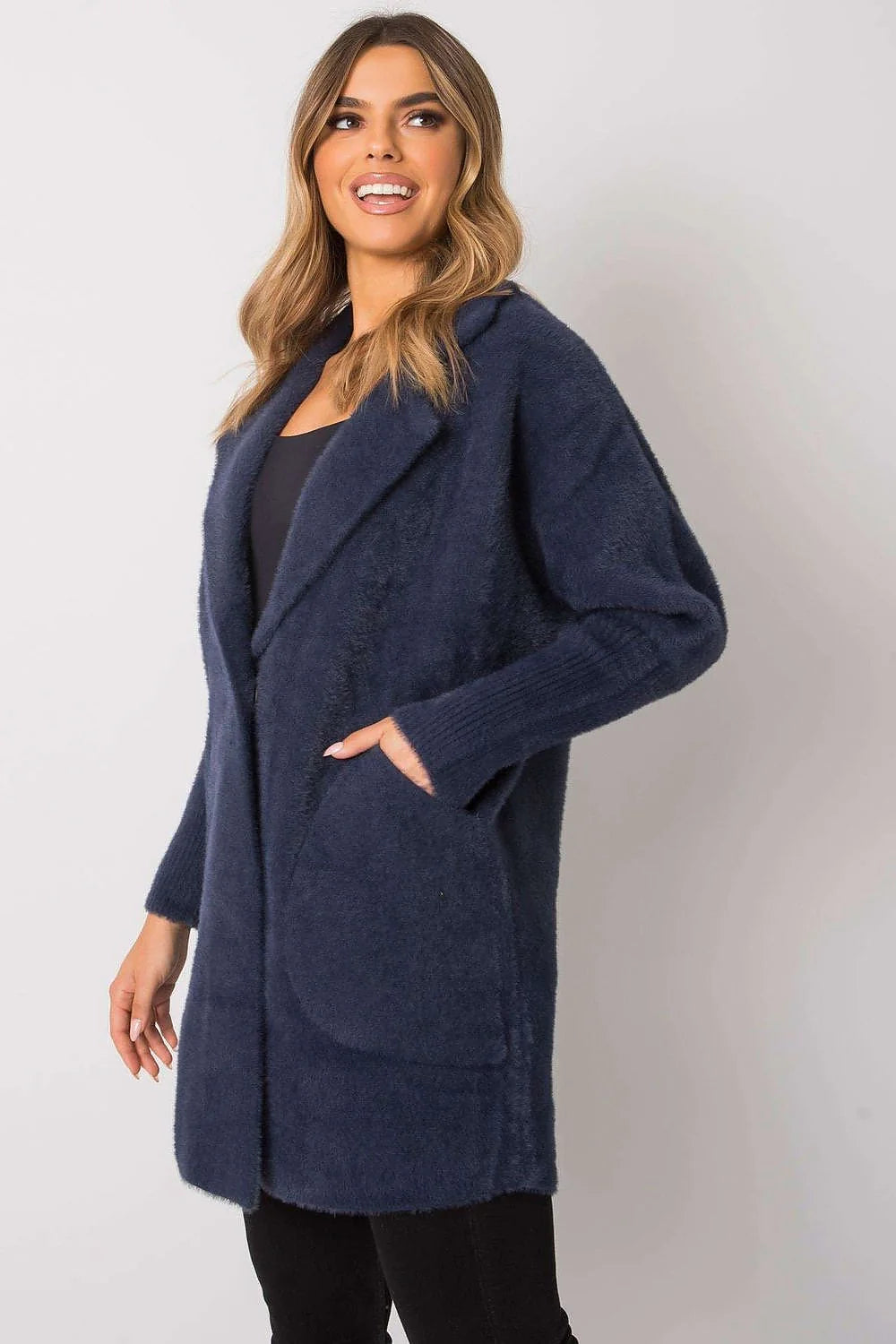 Navy blue fuzzy cardigan with pockets and ribbed cuffs, worn by a model.