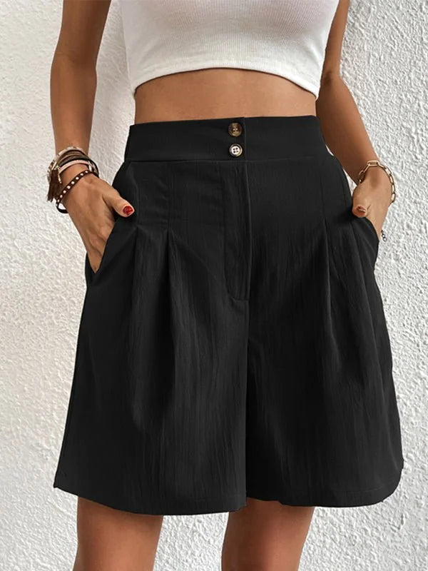 Black high-waisted shorts with pleated front and button detail, on model.