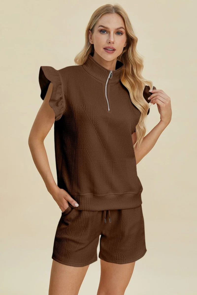 Brown textured short suit with ruffled short sleeves and a quarter-zip neckline on a model.